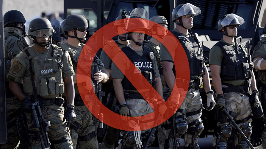 Police in riot gear watch protesters in Ferguson, Mo. on Wednesday, Aug. 13, 2014. On Saturday, Aug. 9, 2014, a white police officer fatally shot Michael Brown, an unarmed black teenager, in the St. Louis suburb. (AP Photo/Jeff Roberson)